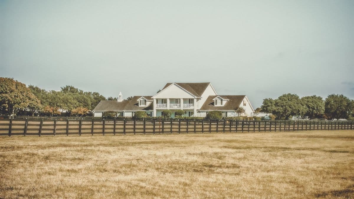 White ranch house behind a wooden fence on Texas grassland